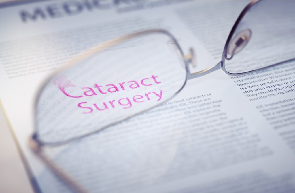 Pair of glasses laying upside down on a medical journal with the words Cataract Surgery in focus showing through the right lense in pink.