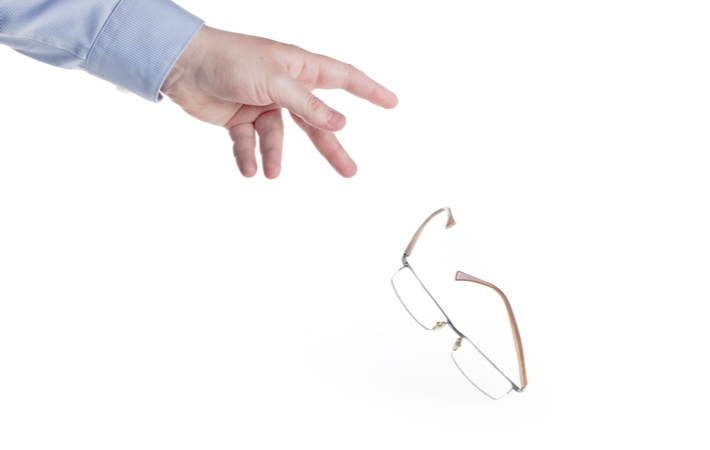 A man's hand throwing away glasses in front of a white background