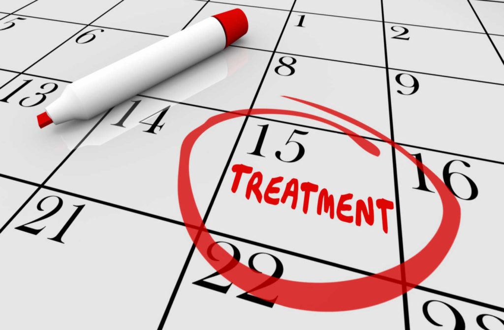 A calendar with the word "treatment" written and circled in red with the red pen laying beside.