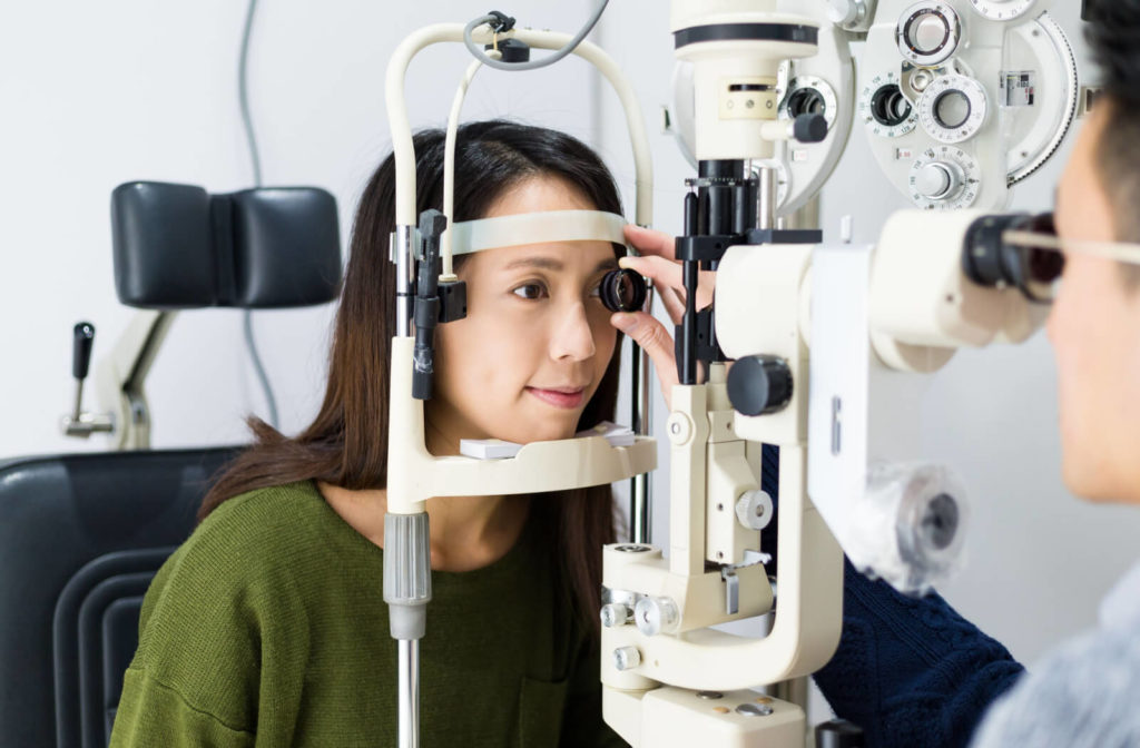 A woman is getting her eyes checked for glaucoma by an optician with a tonometer.