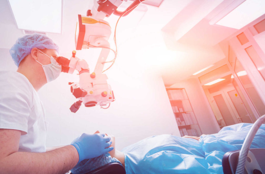 An eye doctor looking through as laser examining instrument before performing LASIK for a woman who is lying in patient clothes under the laser eye operating instrument.