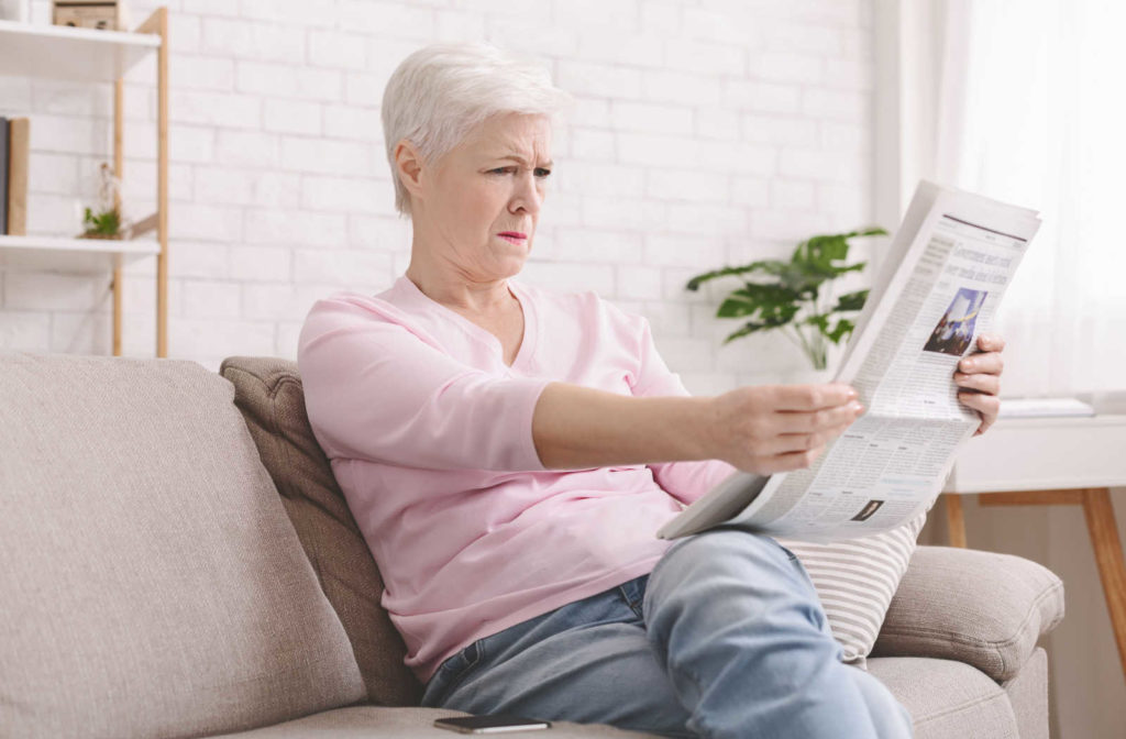 A woman having difficulty reading the newspaper after eye surgery due to natural development of presbyopia.