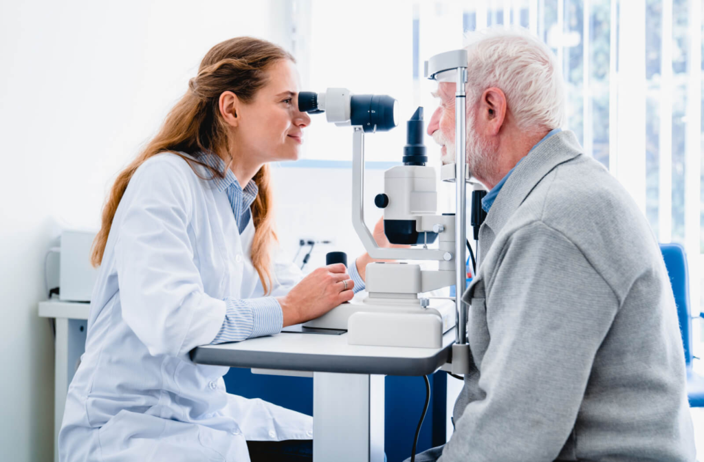 A senior man and his female optometrist performing an eye exam using a medical device to detect eye problems.