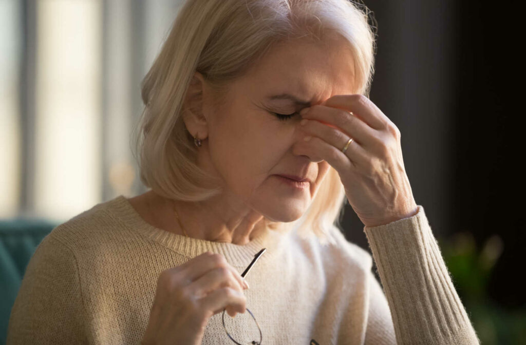 Close-up of a senior lady experiencing headache and pressure on her eyes. Massaging her eyes to relieve the pain.