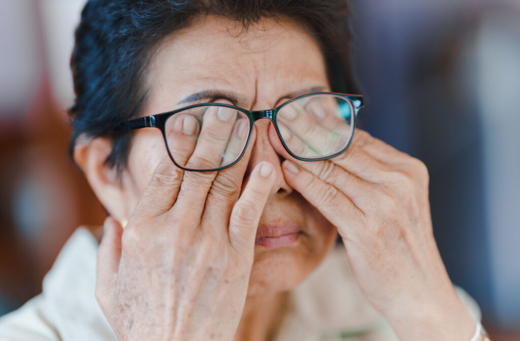 A senior woman pushing her glasses up to rub her eyes with her fingers