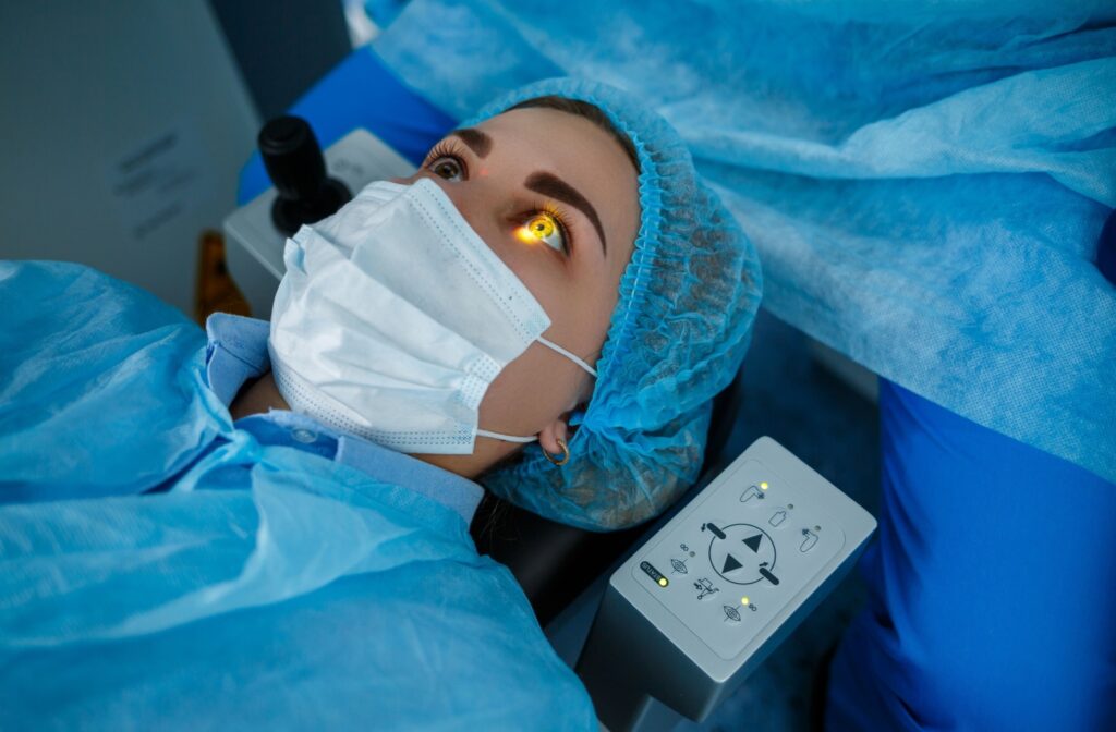 A person lays on a surgery table during LASIK Surgery. A yellow light shines onto their right eye from above.