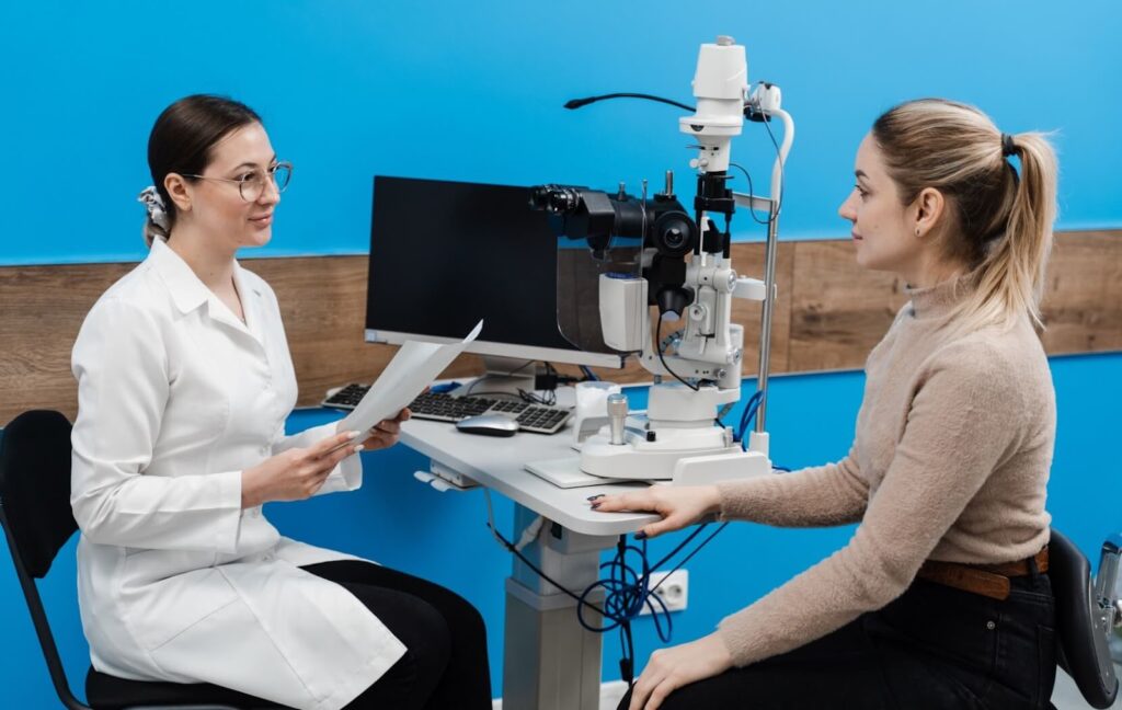 An ophthalmologist sitting with a patient explains the benefits and risks of LASIK surgery to their patient during a consultation.